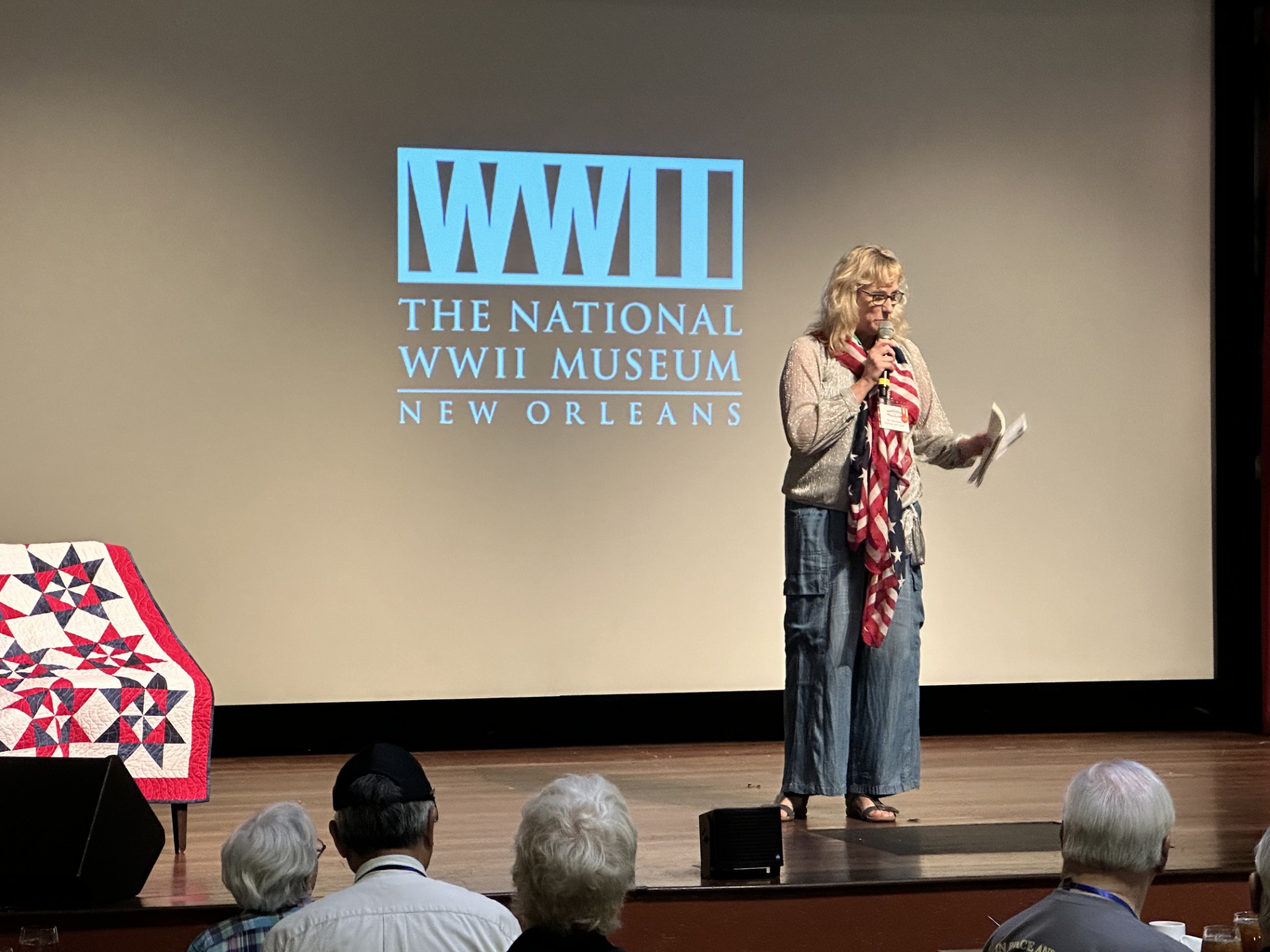 June Klees speaking into a microphone at the National WWII Museum in New Orleans